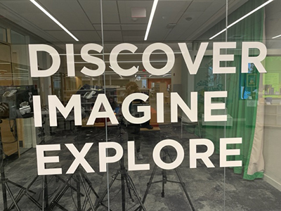 Paper cut out sign that says Discover, Imagine, Explore.
